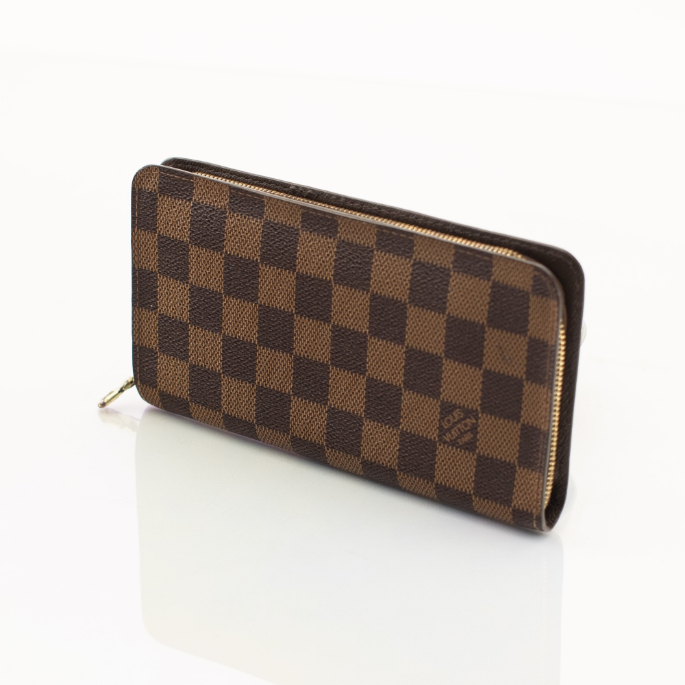 Klassisk Louis Vuitton Wallet i ikonisk Damier Ebene canvas med detaljer i skinn og gullfarget hardware. En tidløs og praktisk lommebok med elegant uttrykk.