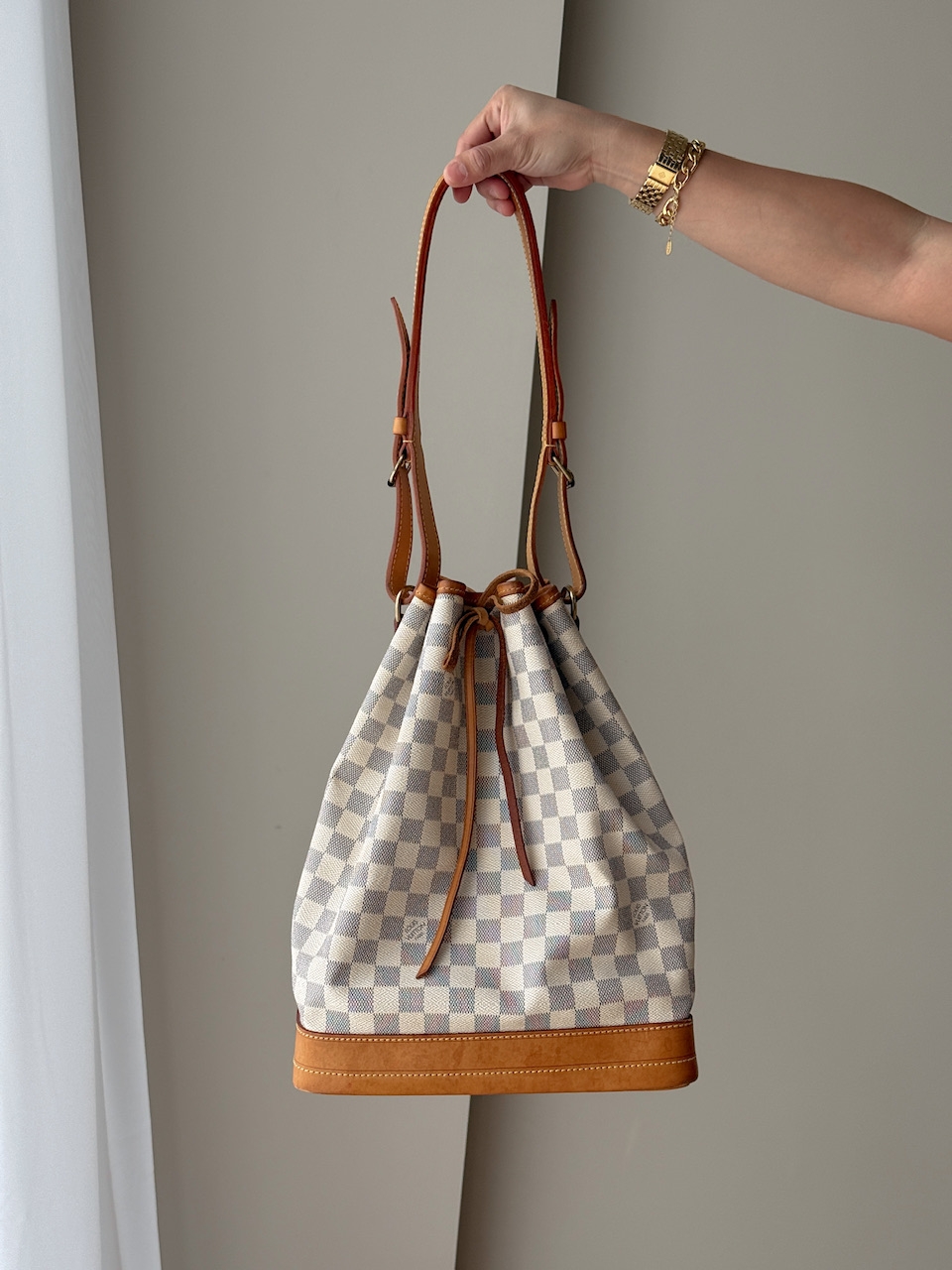 Noé-modellen ble opprinnelig designet for champagneflasker og er i dag en av Louis Vuittons mest ikoniske vesker. Den klassiske bøtteformen med snørelukking gir både funksjonalitet og stil.