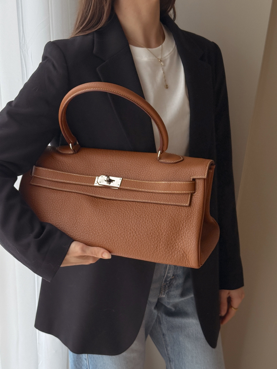 Klassisk Hermès Kelly Shoulder i eksklusivt Taurillon Clémence-skinn med palladium hardware. En elegant og tidløs veske med myk struktur og ikonisk design.
