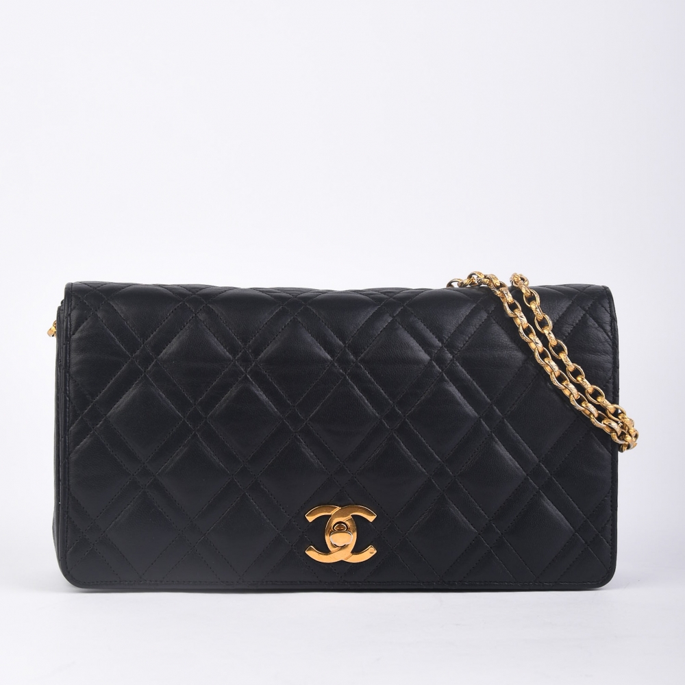 Chanel Classic Flap i sort lammeskinn med 24K gullbelagt hardware og alle originale deler. Produsert i Frankrike – en kulminasjon av Chanels tradisjon og eleganse, perfekt for deg som ønsker en vintage-luksusveske med arvet sjarm.

