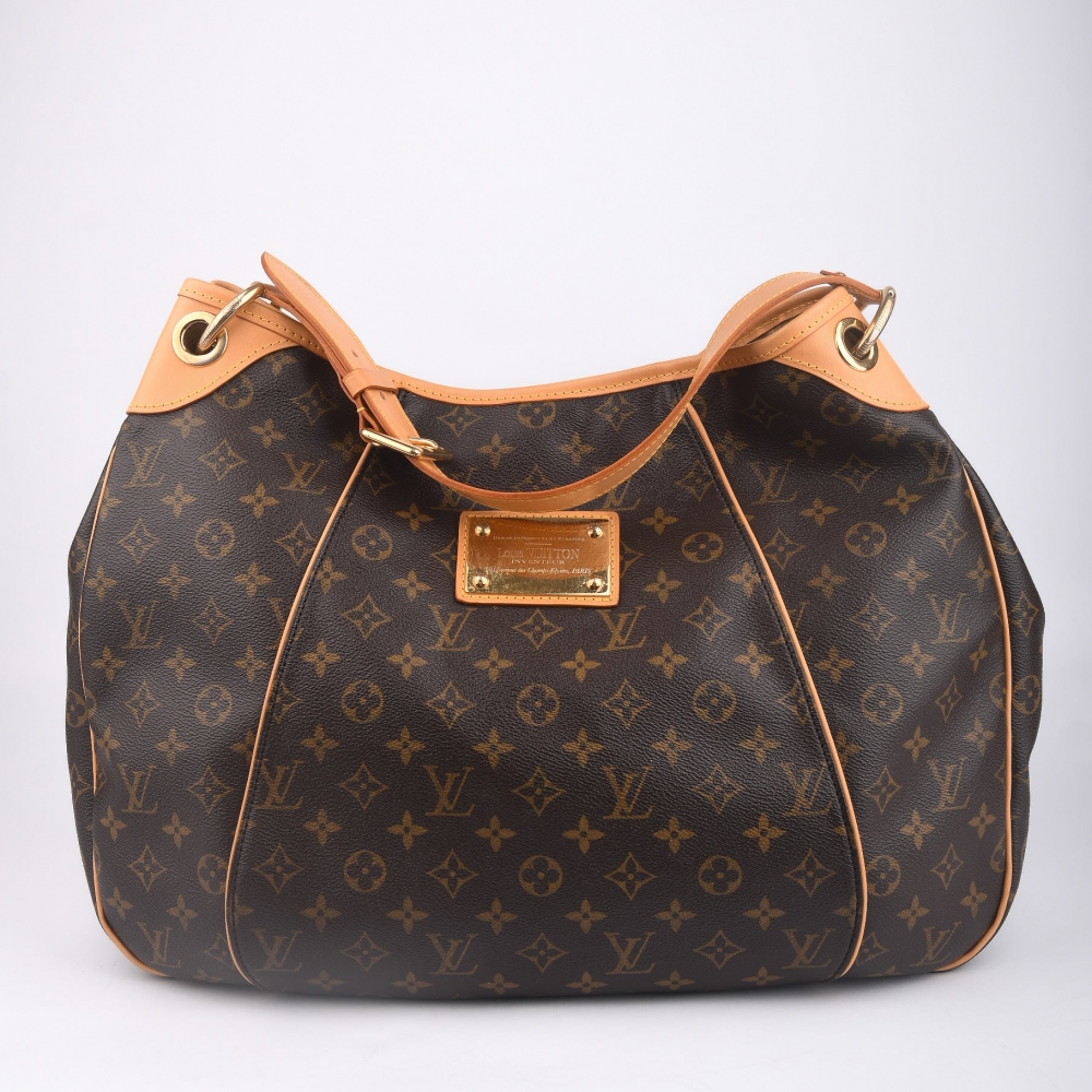 En elegant og ettertraktet skulderveske fra Louis Vuitton – modellen Galliera, laget i klassisk brun monogram canvas med gullfarget hardware og helt nytt skinn. Produsert i USA i 2009, og kjent for sin myke fasong, komfortable bærelengde