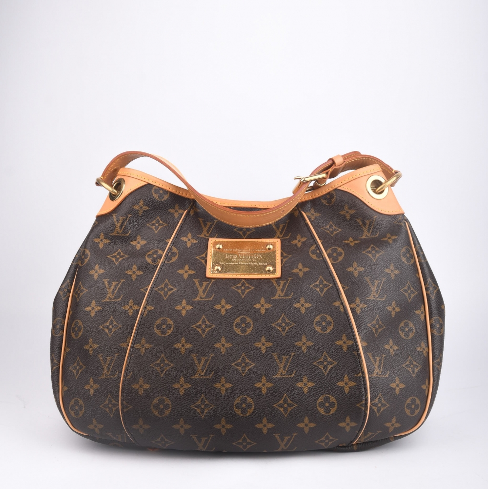 En elegant og ettertraktet Louis Vuitton Galliera fra 2009, laget i klassisk brun monogram canvas med gullfarget hardware og helt nytt skinn. Produsert i Frankrike, og kjent for sin myke form, komfortable bærelengde og ikoniske LV-plakett i front.